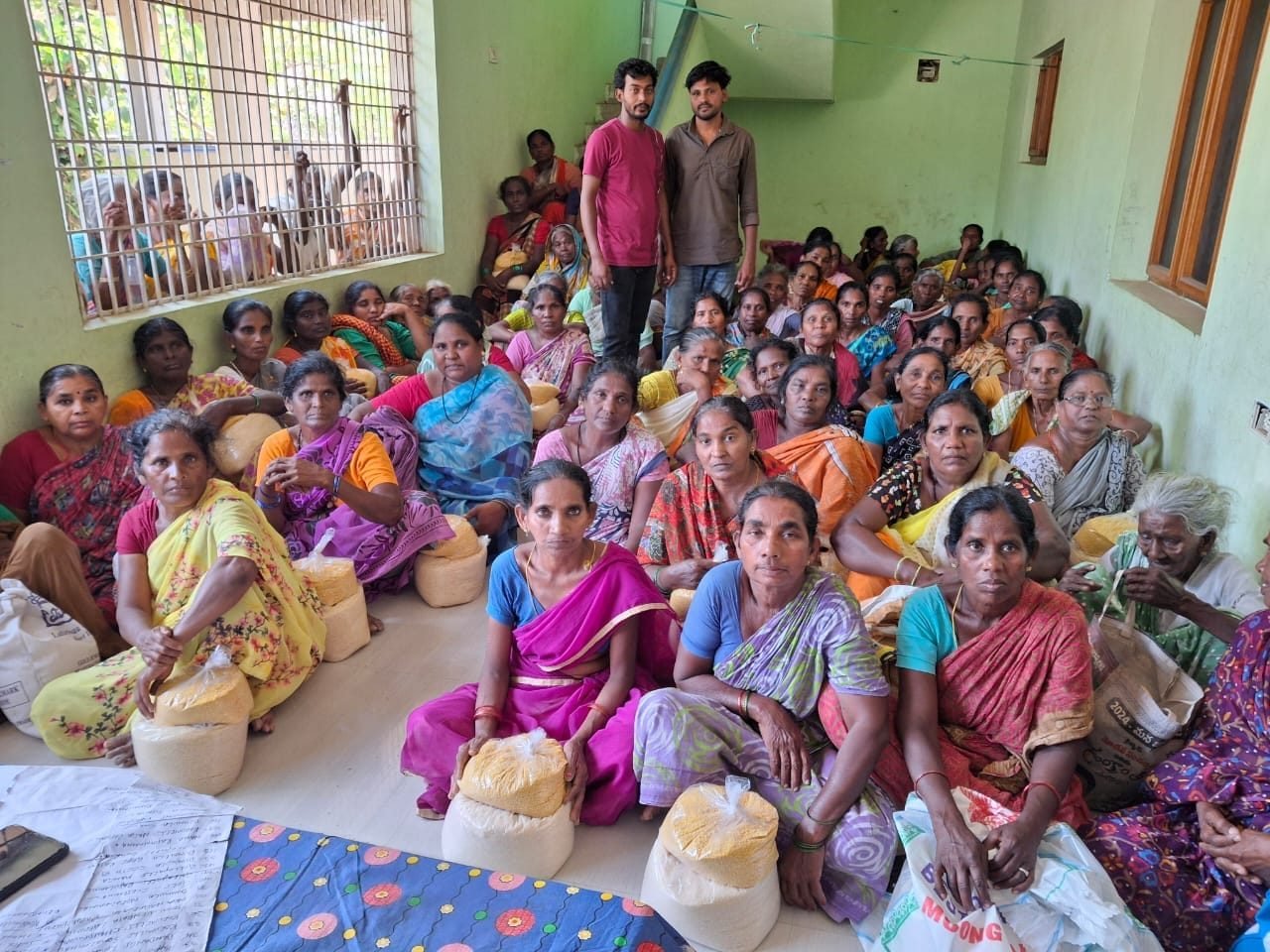 Widows seated with sacks of rice and lentils received from Bethel Mission